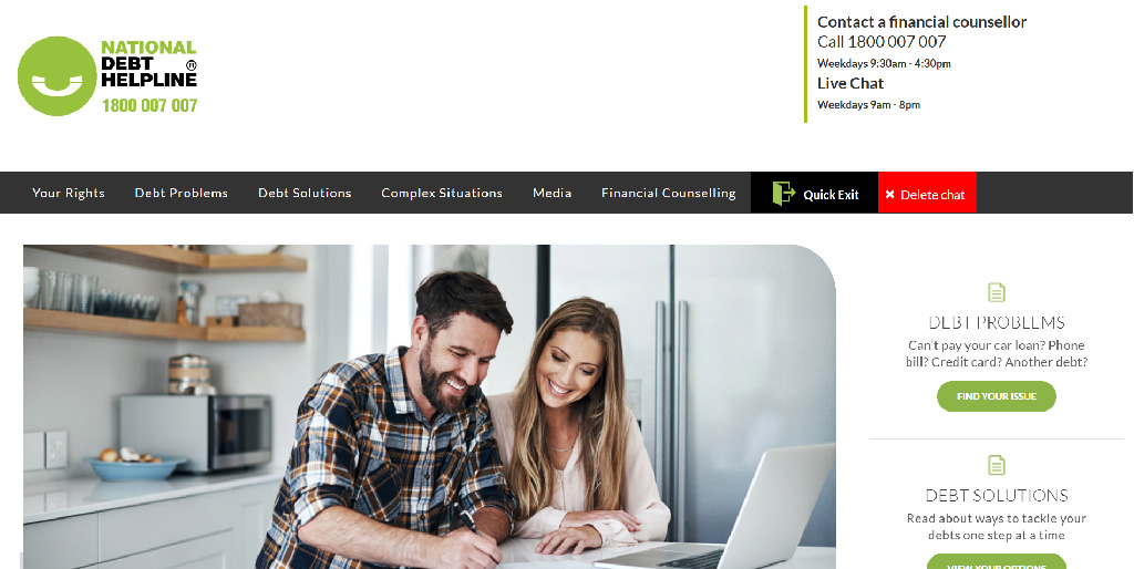 Couple reviewing debt solutions on laptop in kitchen.